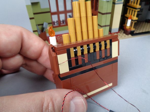 As shown by the two green arrows in the second photo, make sure the candle light wire runs between the tan studs toward the back of the organ.