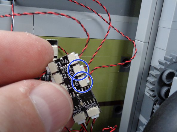 As shown by the two blue circles in the second photo for this step, connect the two red LED lights to plugs #5 and #6 on the BRANCH06X adapter board.