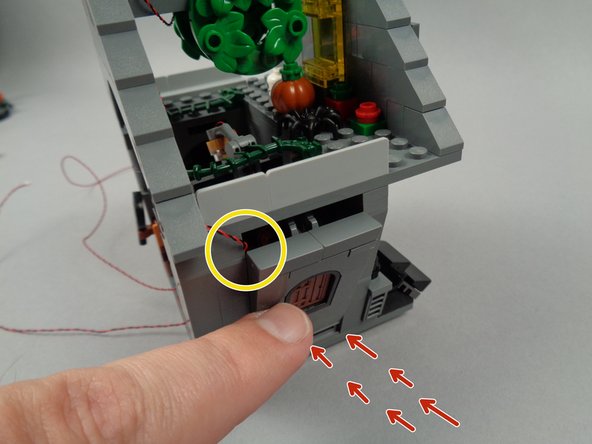 As shown by the yellow circle in the first photo for this step, orient the attic light wire to the corner of the wall opening, then as shown by the red arrows, press the wall section until it snaps back into place.