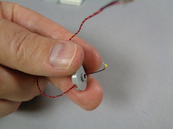 As shown in the first photo for this step, carefully bend the round white LED light board so it is at a 90-degree angle to its wire.