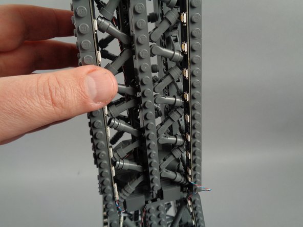 As shown in the photos for this step, attach the top of strip #1 to the tower frame, and re-position brace elements as needed to make room for the LED lights and strip.