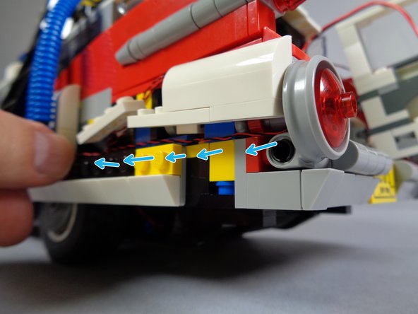 As shown by the blue arrows in the second photo, pass the light wire along the car's frame, then pass it inside and down to the underside.  This is the same path you used for the other two left tail light wires.
