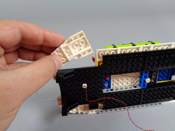 As shown by the red circle in the second photo for this step, remove the plate assembly holding the side roof slopes in place.