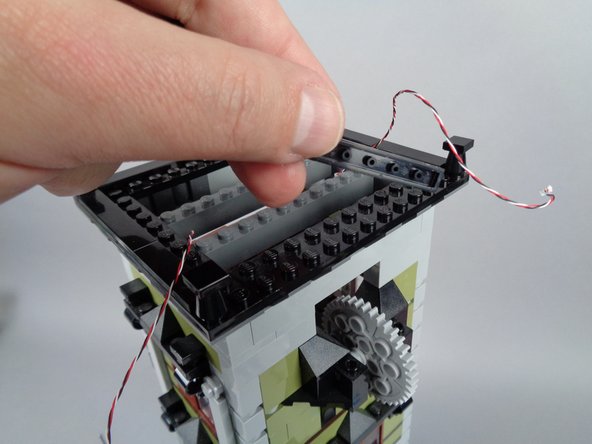 As shown in the photos for this step, remove the long black tile and large black plate along the back side of the tower roof.