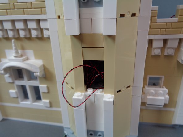Continue carefully re-assembling the castle front as shown in the photos for this step, making sure not to pinch or pull any wires.