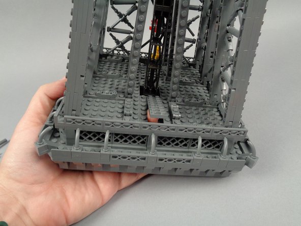 As shown in the first photo for this step, carefully tilt the top tower section, and press upward with your fingers to loosen the 2x8 LEGO plate at the base.