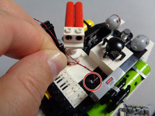 As shown by the red circle in the first photo for this step, you can now pass the light wire for the strobe down through the same hole as the red roof light wire passes.