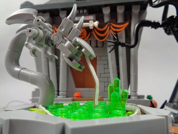 As shown in the second photo for this step, pass the short end of the fountain light strip into the monster's mouth, bending it a little so it looks like a stream of water is coming out of the mouth.