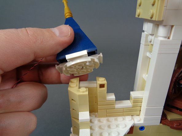 As shown in the photos for this step, remove the small tower top above the kitchen, and attach a warm white Pico LED light to the center using the sticky square you attached in the previous step.