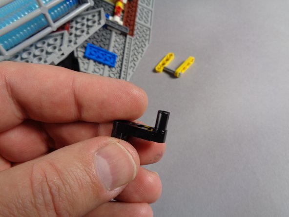 Remove one of the black levers from the Core Parts bag, and attach it to the underside of the Falcon's outer frame as shown in the second and third photos.