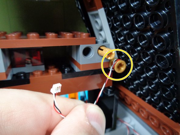 As shown by the yellow circle in the third photo for this step, finish running the 3-wire cable by wrapping it several times around the gold Technic pin.