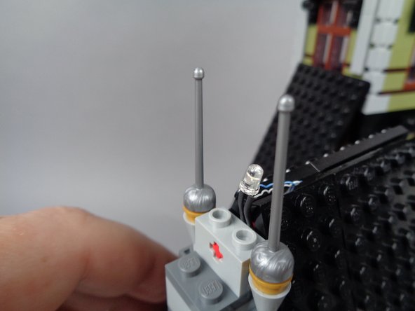 As shown in the third photo for this step, secure the second rooftop lightning LED light by pressing it into the space between the roof and the light bluish gray brick.