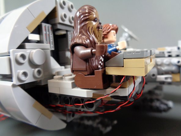 As shown in the photos for this step, run the four cockpit control panel wires under the cockpit and back through the open area toward the back of the cockpit passage.