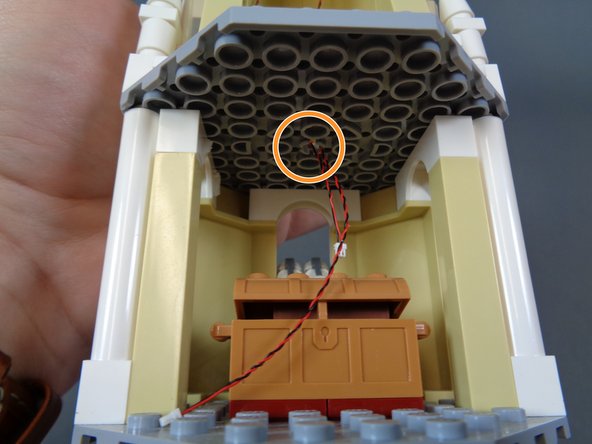 As shown by the orange circle in the third photo, the two light wires should extend down to the lowest level of the top tower through the hole in the ceiling.