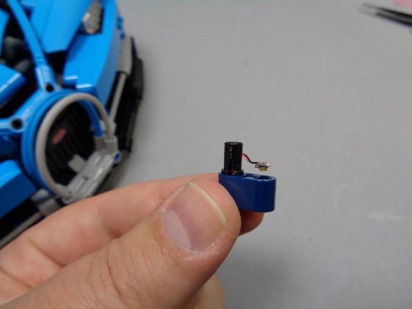 As shown in the third photo, the LED cable should come through the slot in the black Technic pin, and the LED should bend to face toward the blue Technic beam.