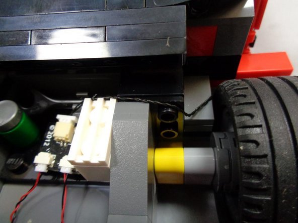 As shown by the orange arrow and the third photo, make sure the black connecting cable extends behind the white brick.