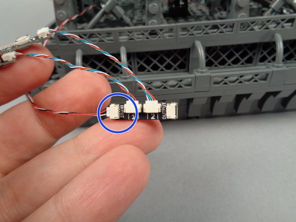 As shown by the blue circle in the photo for this step, take the last light strip pair and adapter board, and connect the other end of the control cable to the INPUT plug on the next adapter board.
