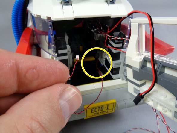 As shown by the yellow circle in the second photo, you should be able to pull the tail light wire tight from inside the Ecto-1.
