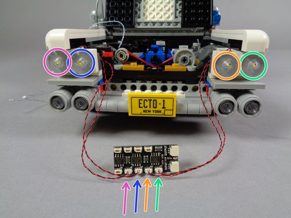 Re-attach the second headlight bank as shown in the photo for this step, making sure the light wires pass over the TOP of the white plate.