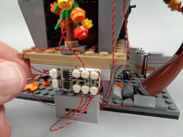 As shown in the photos for this step, attach the BRANCH06X driver board to the back side of Jack's house with the large sticky square.