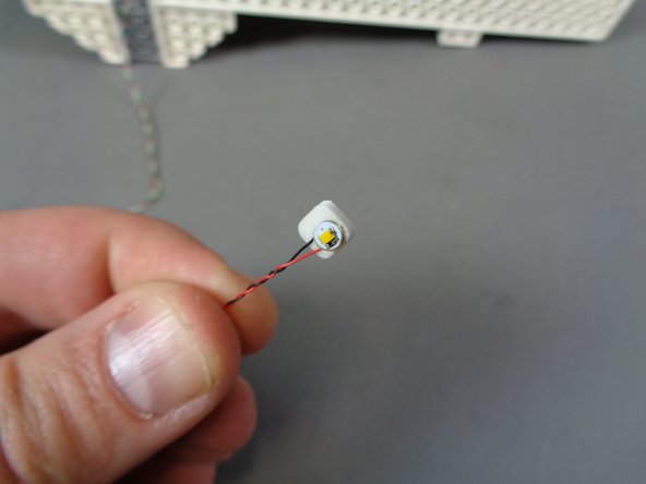 As shown in the first photo, take the fourth and final warm white Pico LED light in the &quot;Middle Level Interior Lights and Parts&quot; bag and place a sticky square on the back.