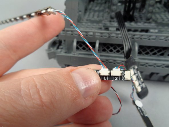 As shown in the second and third photos for this step, take the light strips connected to plug #1 on the adapter board and pass them through the first tower pillar.