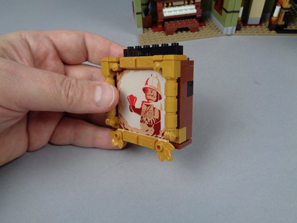 As shown in the photos for this step, disassemble the back side of the explorer painting so you can remove the panel with the Sphinx and the brown brick underneath it.