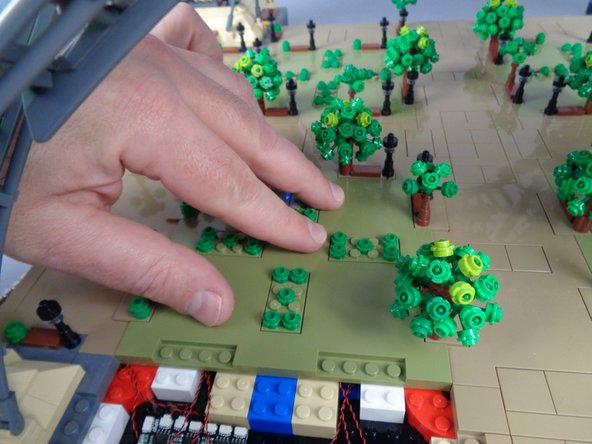 As shown by the two yellow circles in the second photo, before pressing all the way down on the panel to fully re-attach it, make sure the six LED light wires for the Panel 1 lamp posts pass through the gaps between the white and tan bricks.