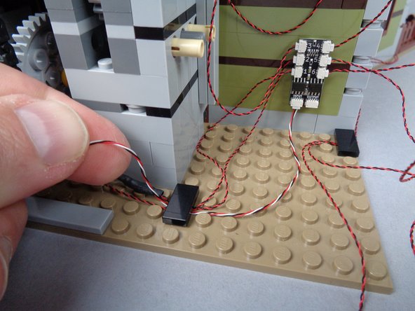 As shown in the photos for this step, route the long 3-wire connecting cable toward the main effect controller.