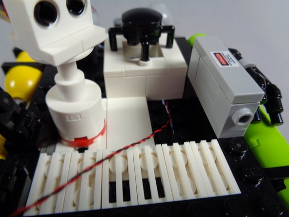 The orange circle in the second photo shows some excess (slack) wire for the cool white strobe light.  This is needed if you want to mount the LED light inside the larger 2x2 round steering brick later.  If you do want to do this, you should leave more slack in the LED wire than is shown in the photo-- at least twice as much.