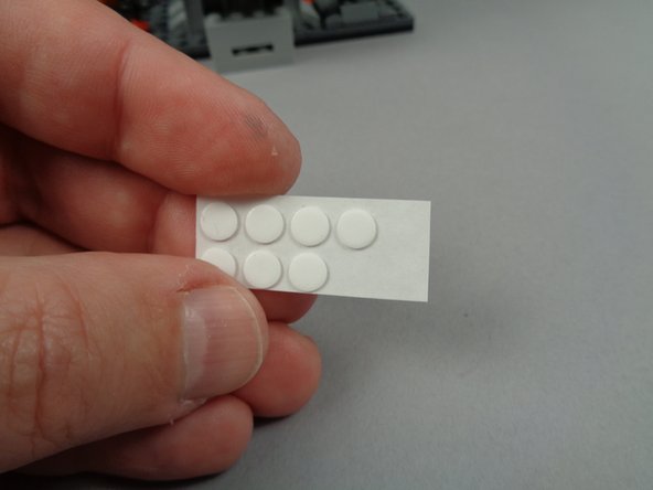 As shown in the second and third photos for this step, take two small sticky discs and attach them to the back of the two green LED lights.