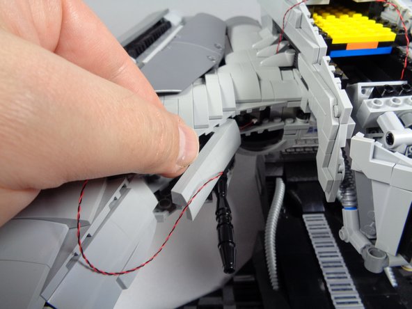 As shown in the photos for this step, follow the same procedure to attach the second gun and run its light wire into the center of the head section.