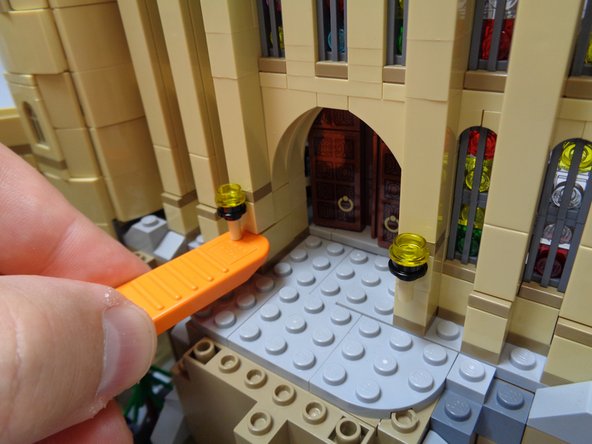 As shown in the first and second photos, use a brick separator to remove the torch to the left of the entry door.