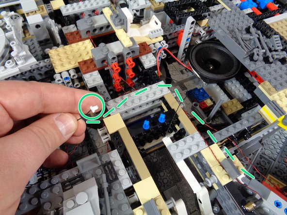 As shown by the dotted green line and green circle in the first photo, run the other end of the magnetic switch wire behind the boarding ramp area and back toward the location of the TRUNK08 master controller.