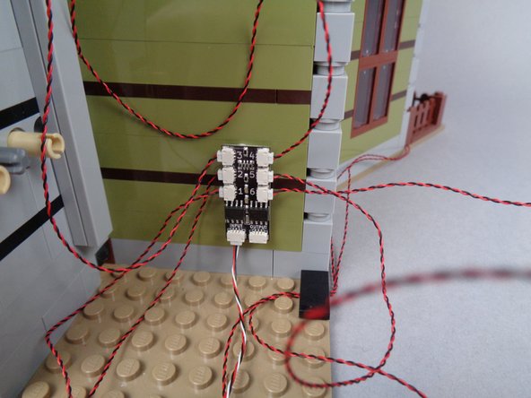 As shown in the photos for this step, use two sticky squares to attach the second BRANCH06X adapter board to the back wall of the mansion.