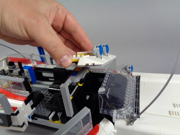 As shown by the green arrows in the first photo, you can use your brick separator to gently pry the white slopes free of the top of the front windshield, which will make removing the front roof section easier.