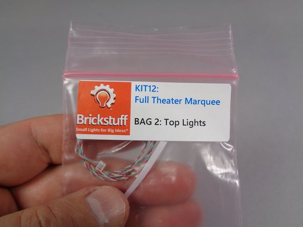 As shown in the first and second photos for this step, carefully remove the white light strip from Bag 2 (&quot;Top Lights&quot;) in your kit.