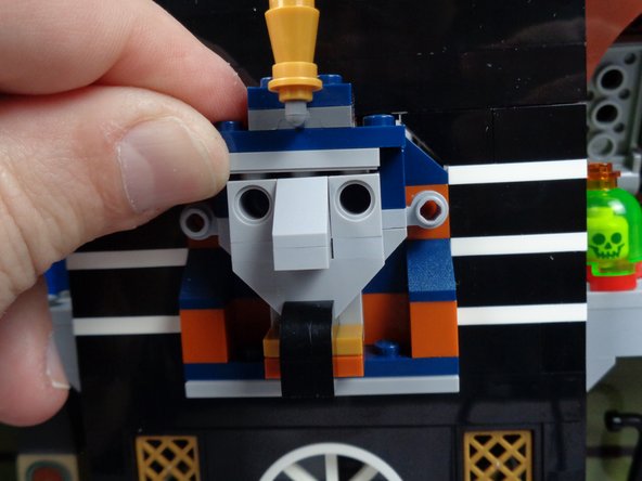 As show in the photos for this step, press upward on the top of the pharaoh's headgear to make room to remove the face parts.