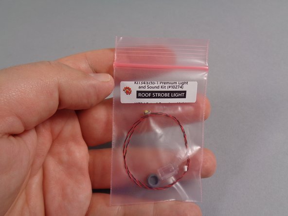 As shown in the first photo for this step, remove the small pink bag labeled &quot;Roof Strobe Light&quot; from the &quot;Roof Parts&quot; bag.
