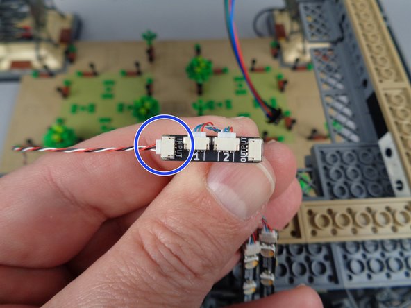 As shown in the first photo for this step, carefully reach under the center of your tower to find the loose control cable coming from the previous adapter board and first set of light strips.