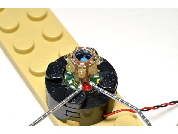 This photo shows a detail view of using the unfolded paperclip to jump the two metal contacts on either side of the red dot.