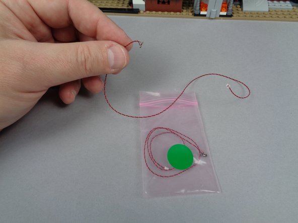 As shown in the second photo for this step, remove one of the lights from the bag.  Keep the second light inside the bag so you can identify the second green light later.
