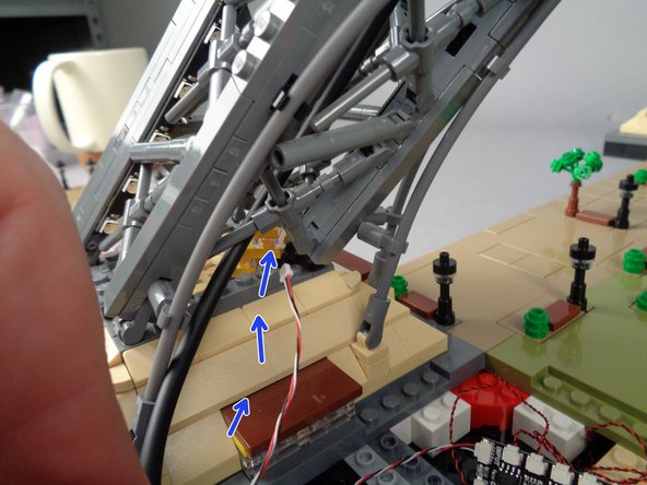 As shown by the blue arrows in the second and third photos for this step, wrap the control cable around the USB-C power cable and then up into Pillar 1 of your Eiffel Tower.