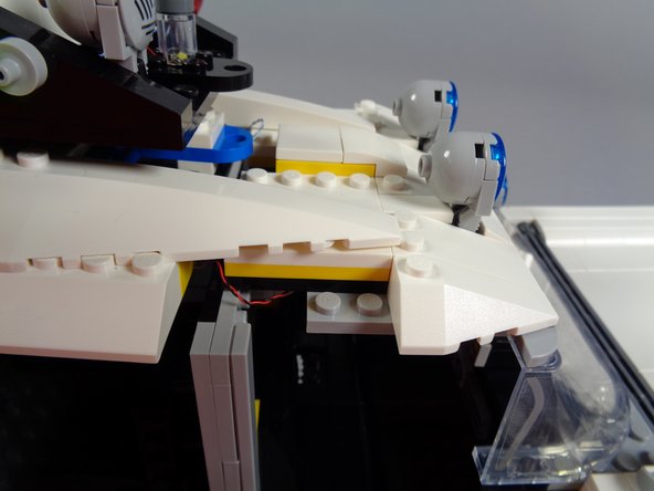 The green circle in the first photo for this step shows the three light wires coming from the front roof section.  Carefully pull these as you re-position the roof.  You want to make sure there is no slack hanging down inside the car, or loose wires that could get caught in the gears.