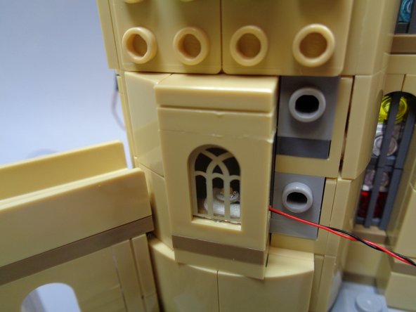 As shown in the second and third photos, carefully insert the first light behind the lower window.  The light should be centered in the back of the window, facing up.