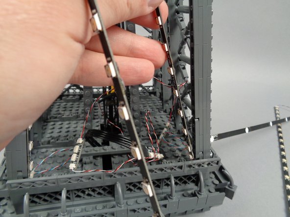 Remove the backs of the sticky dots on the first light strip (connected to plug #1 of the adapter board), and attach the strip to the tower frame as shown in the photos for this step.