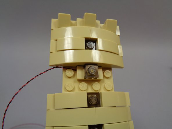 As shown in the first photo, carefully re-attach the pre-lit window by running the wire to one side and to the top of the light, then re-attaching to the main tower structure.