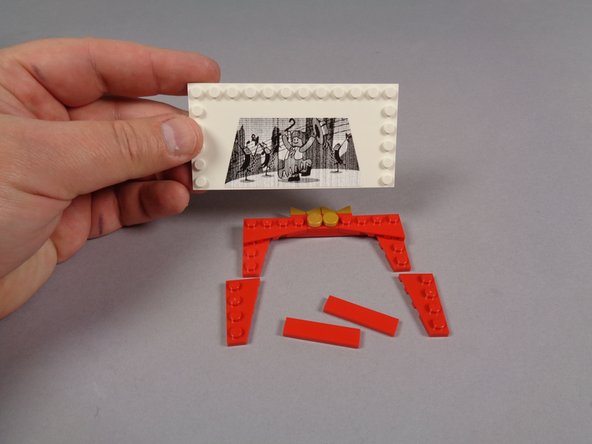 As shown in the first photo for this step, remove all of the existing LEGO® parts from the large white tile with the movie image sticker.