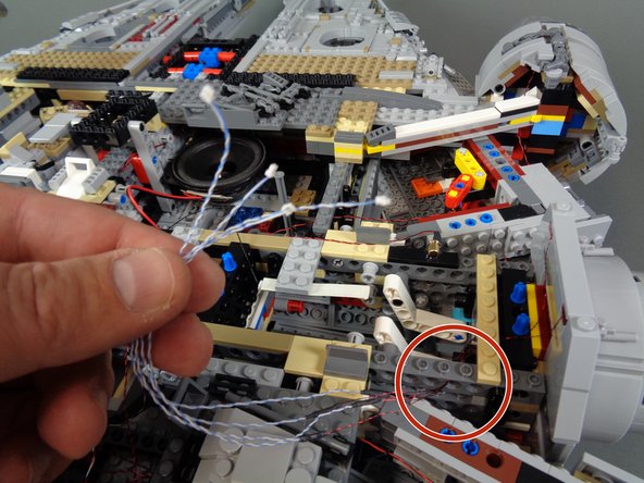 As shown by the orange arrows in the first photo, make sure the top light wires run flat down the back of the docking bay cap and that there is extra slack in the wires so they do not become pinched or cut when the top of the docking bay is re-attached at the end of the assembly process.