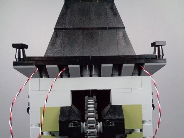 As shown in the photos for this step, replace the large black plate and large black tile you removed earlier onto the top of the roof.